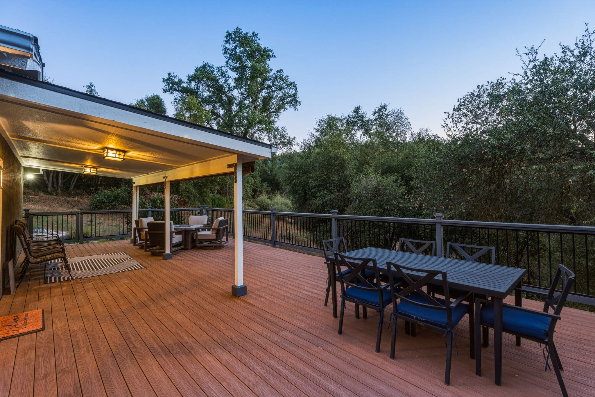 Outdoor dining and fire table on the wrap-around deck at sunset